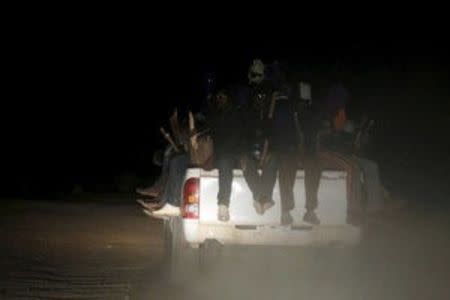 Migrants sit on the back of a truck as it is driven through a dust road at night in the desert town of Agadez, Niger in this May 25, 2015 file photo. REUTERS/Akintunde Akinleye/Files