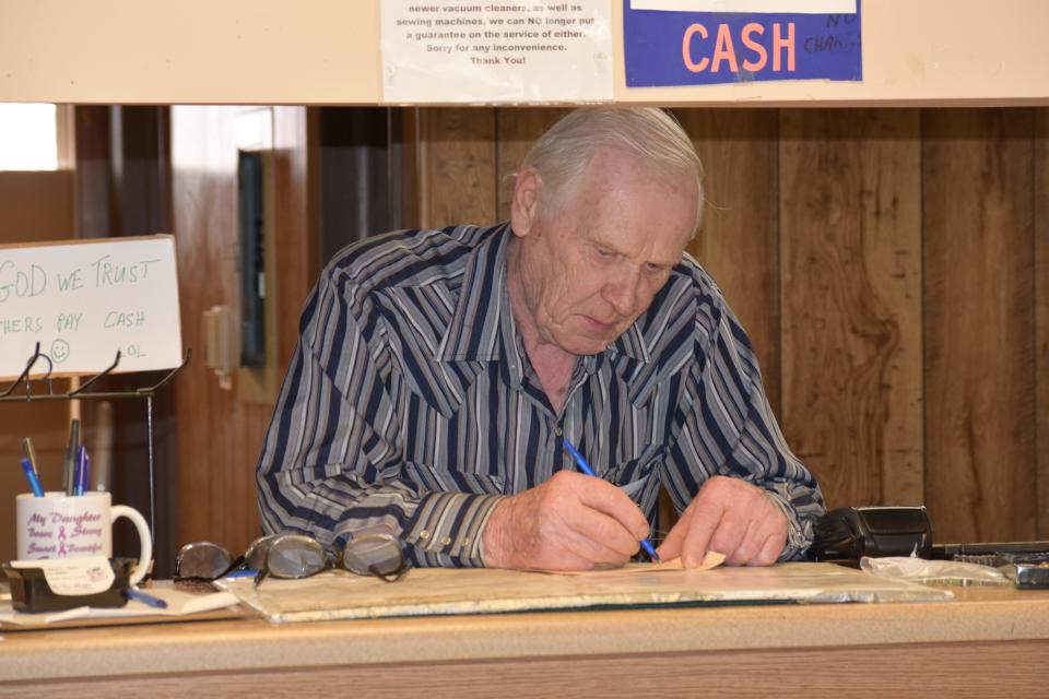 The Vac Shoppe owner Wolfgang Heyn works behind the counter of his store in Pueblo, which is going out of business at the end of May after 41 years.