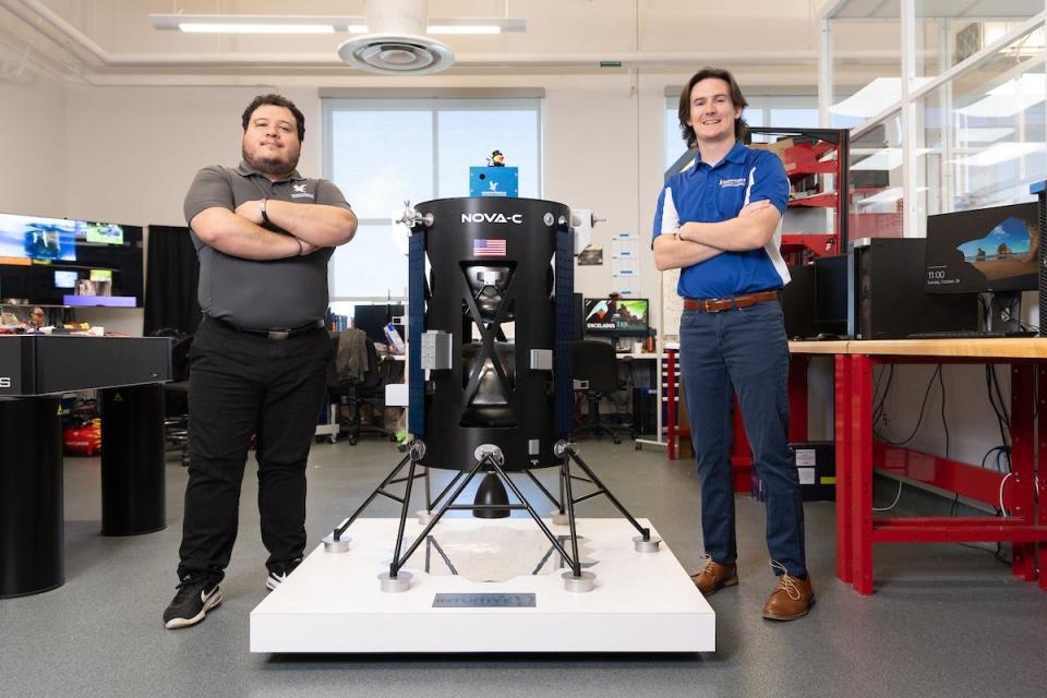 Embry-Riddle Aeronautical University Ph.D students Daniel Posada and Chris Hays pose next to a model of the Nova-6 lunar lander that carries the EagleCam, a device they helped build.