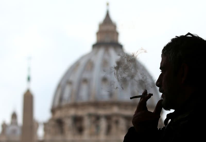 A man smokes a cigarette in front of St. Peter Square, in Rome