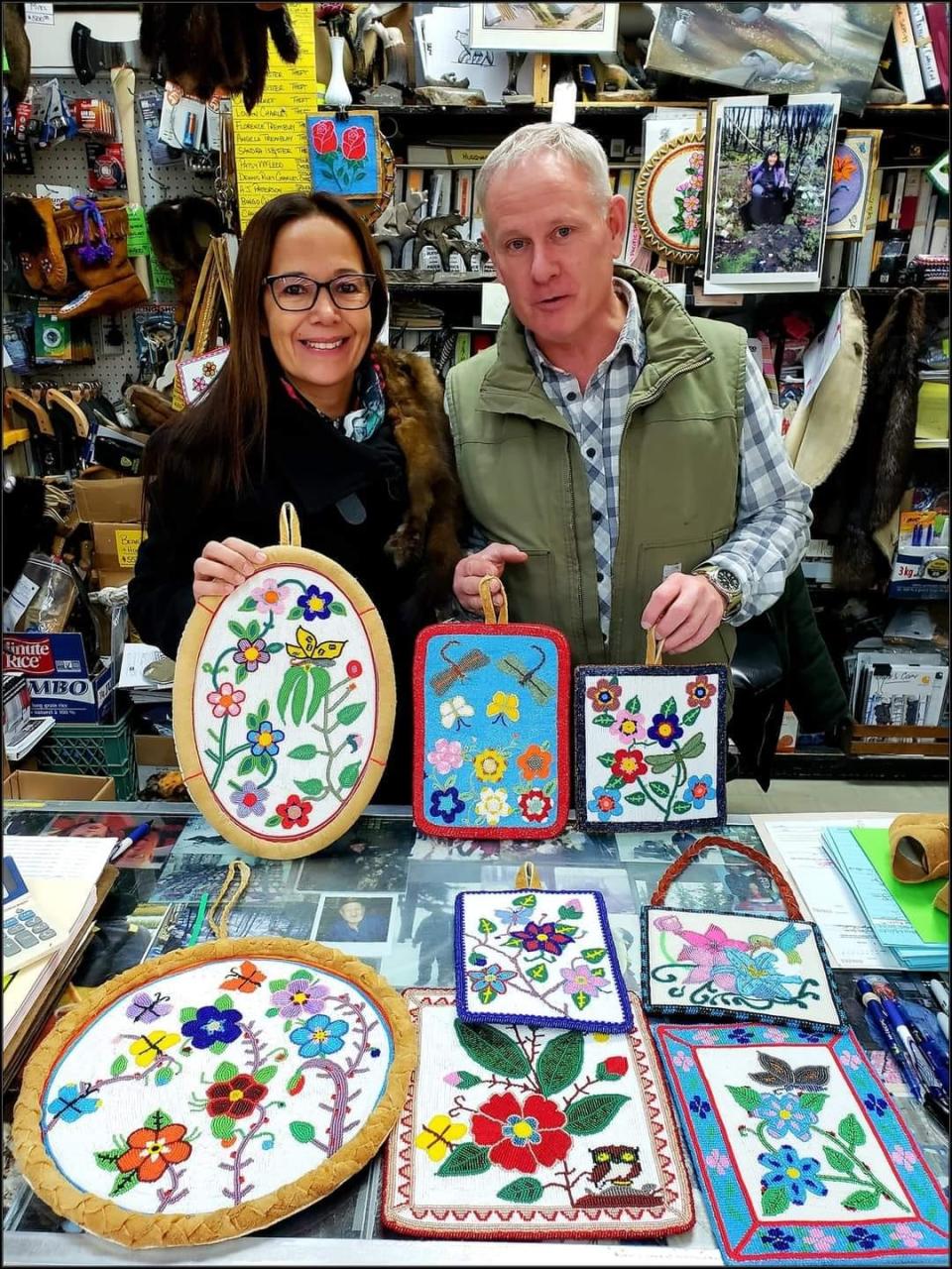 Tammy Cook-Searson and Scott Robertson stand behind the trading desk behind a grouping of intricate beadwork. 