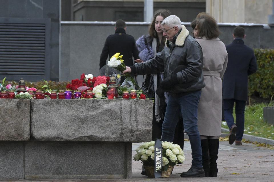 FILE - Oleg Orlov, a member of the Board of the International Historical Educational Charitable and Human Rights Society 'Memorial' (International Memorial), foreground right, lays flowers at the monument, a large boulder from the Solovetsky islands, where the first camp of the Gulag political prison system was established, near the building of the Federal Security Service (FSB, Soviet KGB successor) in Lubyanskaya Square in Moscow, Russia, Sunday, Oct. 29, 2023. (AP Photo/Dmitry Serebryakov, File)