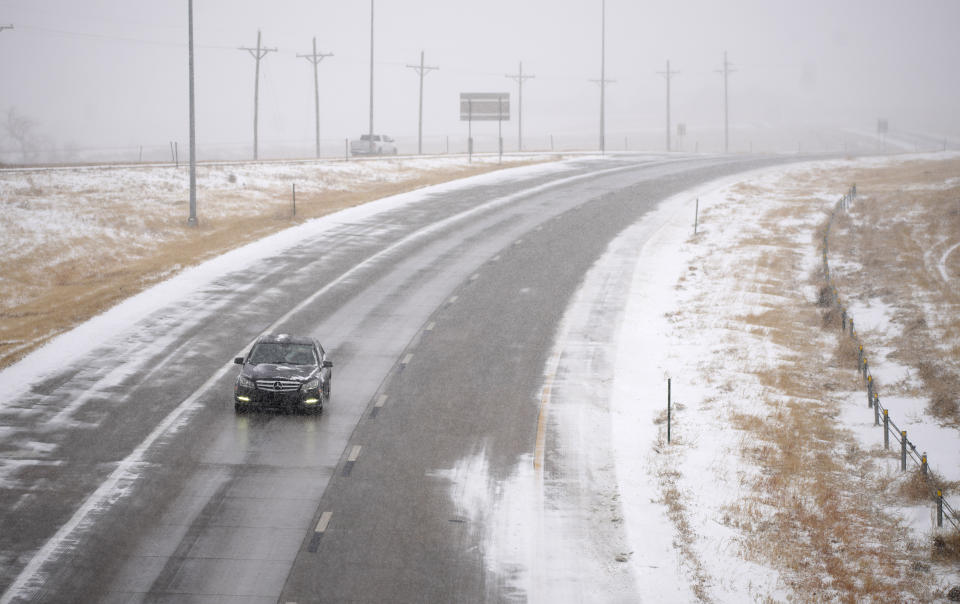 A lone vehicle moves along the westbound lanes of Interstate 70 near East Airpark Road, Tuesday, Dec. 13, 2022, in Aurora, Colo. A massive winter storm has closed roads throughout northeast Colorado. (AP Photo/David Zalubowski)