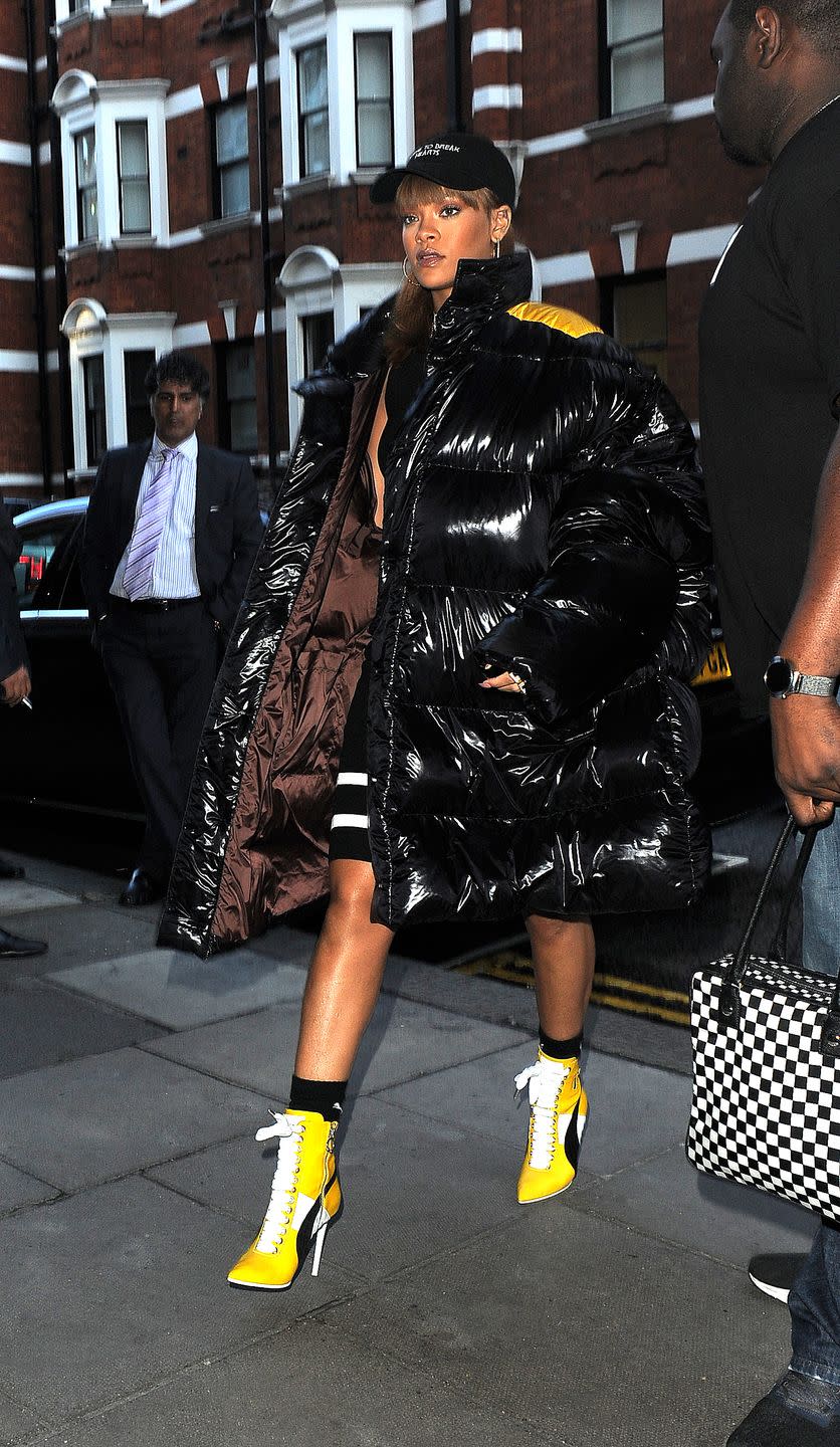 <p>Rihanna bundled up for a day of shopping at Harrods in London wearing a Raf Simons black puffer coat, yellow booties and her signature dad hat. </p>