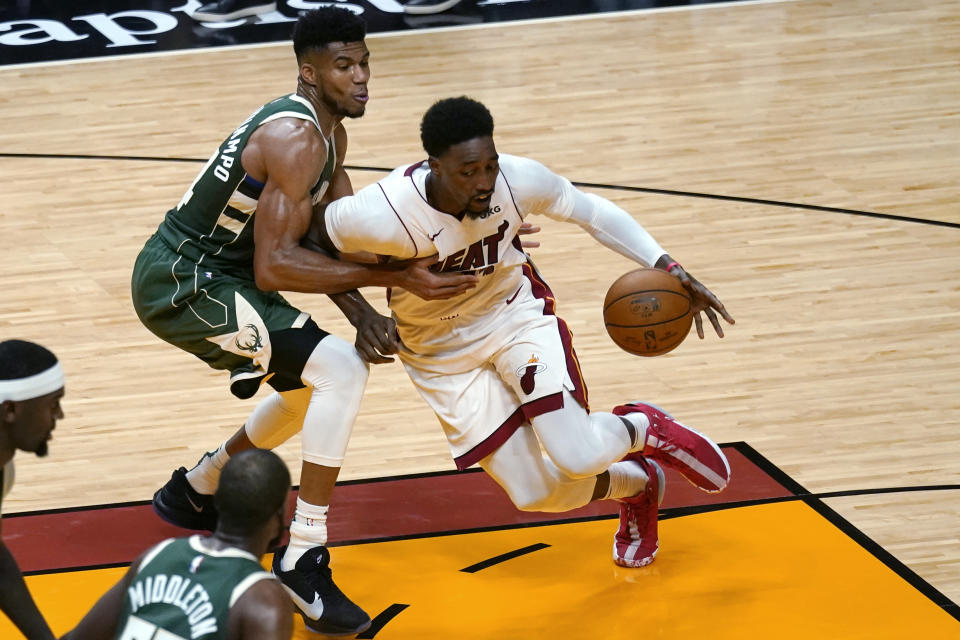 Miami Heat center Bam Adebayo, right, controls the ball as Milwaukee Bucks forward Giannis Antetokounmpo, back left, defends during the first half of an NBA basketball game Wednesday, Dec. 30, 2020, in Miami. (AP Photo/Lynne Sladky)