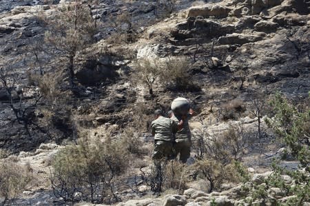Military personnel carry debris on a slope where a missile struck, in Tashkent (also known as Vouno)