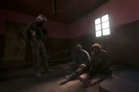 An Syrian Democratic Forces(SDF) fighter stands near what he said was Islamic State fighters held prisioners by them , north of Raqqa city, Syria March 8, 2017. REUTERS/Rodi Said