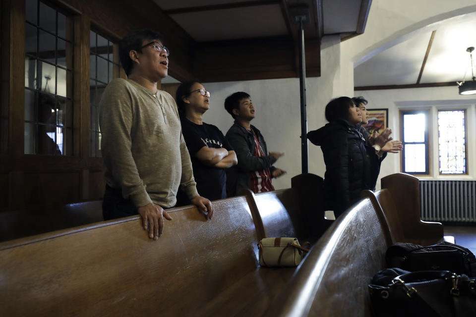 In this Sunday, Feb. 16, 2020, photo, S'Tha Sein, left, and his wife, Phyu Pyar, second from left, immigrants from Myanmar, also known as Burma, stand during services at the Overseas Burmese Christian Fellowship in Boston. The couple are concerned their eldest daughter may not be able to join them after they arrived in Boston in December 2019 following the announcement of a Trump administration policy that is expected to all but shut down family-based immigration from Myanmar. (AP Photo/Steven Senne)