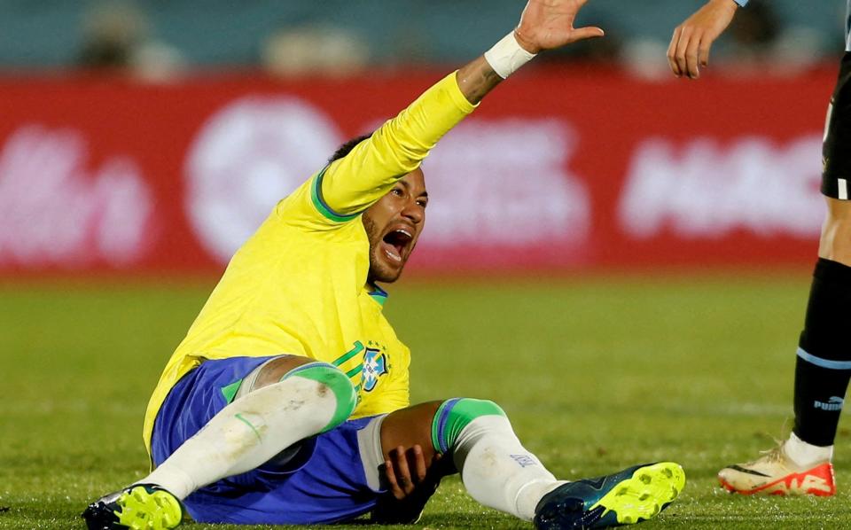 Neymar waves his arm in pain after injuring his ACL playing for Brazil against Uruguay in October