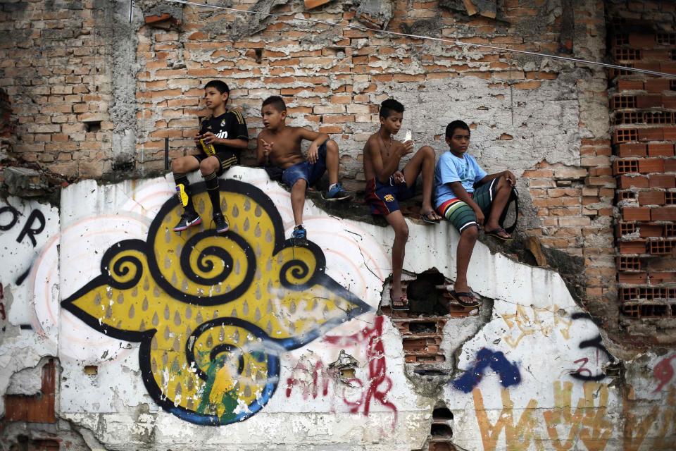 Children watch a soccer match held by activists as part of the "Rebel Cup" in downtown Sao Paulo April 13, 2014. The "Rebel Cup" is an informal tournament bringing together social movements as a way of protest against government spending for the 2014 World Cup in Brazil. The boy (L) wears a T-shirt of Real Madrid and the boy (2nd R) wears the shorts of Barcelona. REUTERS/Nacho Doce (BRAZIL - Tags: SPORT SOCCER WORLD CUP POLITICS)