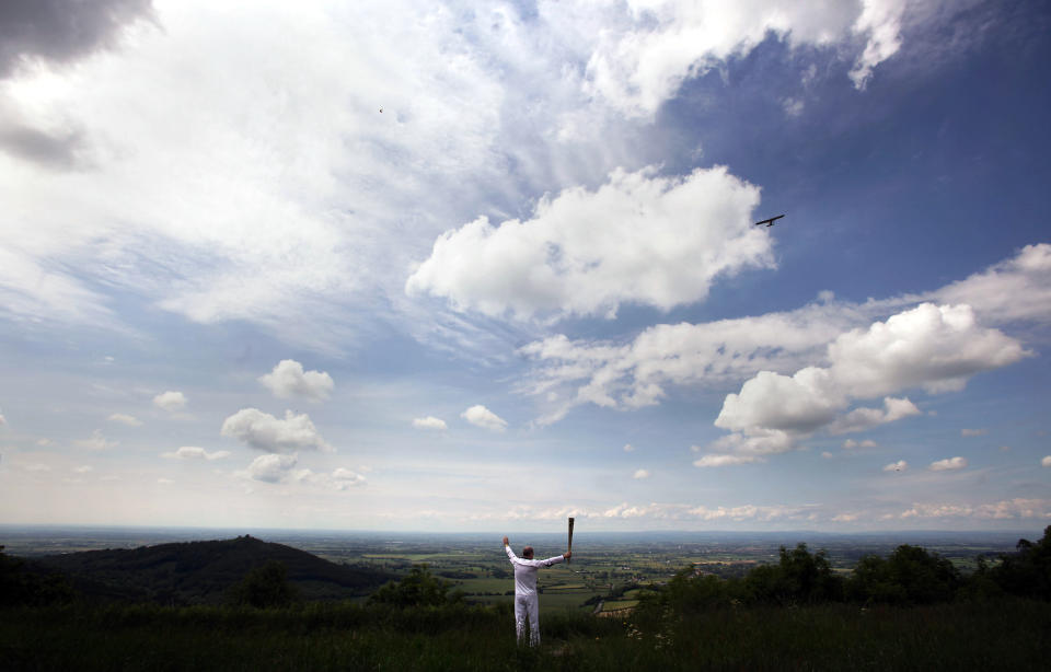 In this handout image provided by LOCOG, Torchbearer 011 Eugene Perry carries the Olympic Flame at Sutton Bank, part of the North Yorkshire Moors National Park, with Vale of York in background on June 20, 2012 in York, England. The Olympic Flame is now on day 33 of a 70-day relay involving 8,000 torchbearers covering 8,000 miles. (Photo by LOCOG via Getty Images)