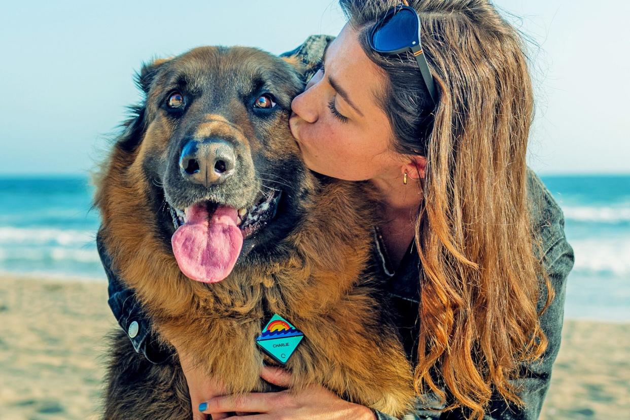 woman kissing dog that is wearing his QALO tag