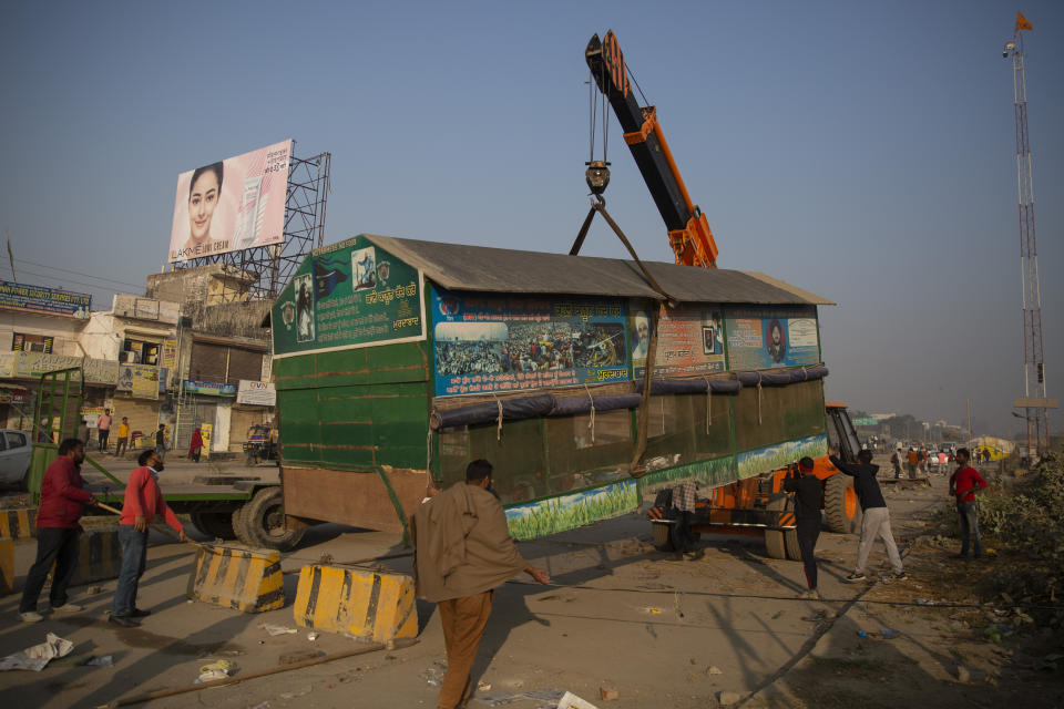 Indian farmers use a crane to lift a temporary structure used during protests as they start vacating the protest site in Singhu, on the outskirts of New Delhi, India, Saturday, Dec. 11, 2021. Tens of thousands of jubilant Indian farmers on Saturday cleared protest sites on the capital’s outskirts and began returning home, marking an end to their year-long demonstrations against agricultural reforms that were repealed by Prime Minister Narendra Modi's government in a rare retreat. (AP Photo/Altaf Qadri)