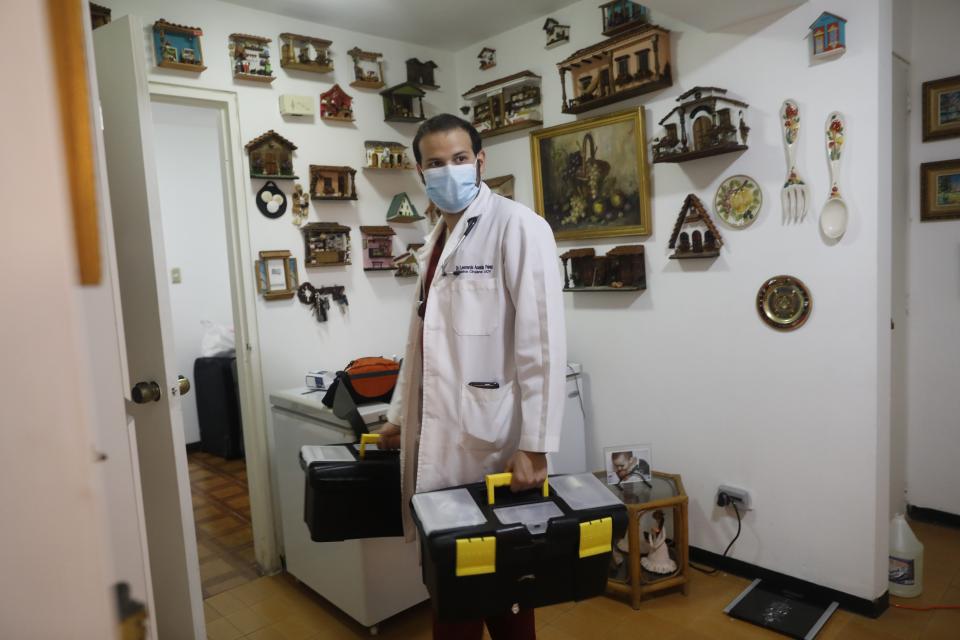 Doctor Leonardo Acosta holds two cases with medical supplies as he leaves the apartment of two patients he just checked on, who suffer from COVID-19 in Caracas, Venezuela, Thursday, March 18, 2021. (AP Photo/Ariana Cubillos)