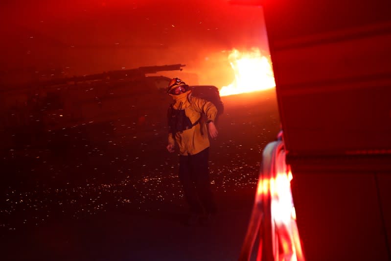 A firefighter gestures and hurries a man to direct a fire engine into position during the wind-driven Kincade Fire in Windsor, California