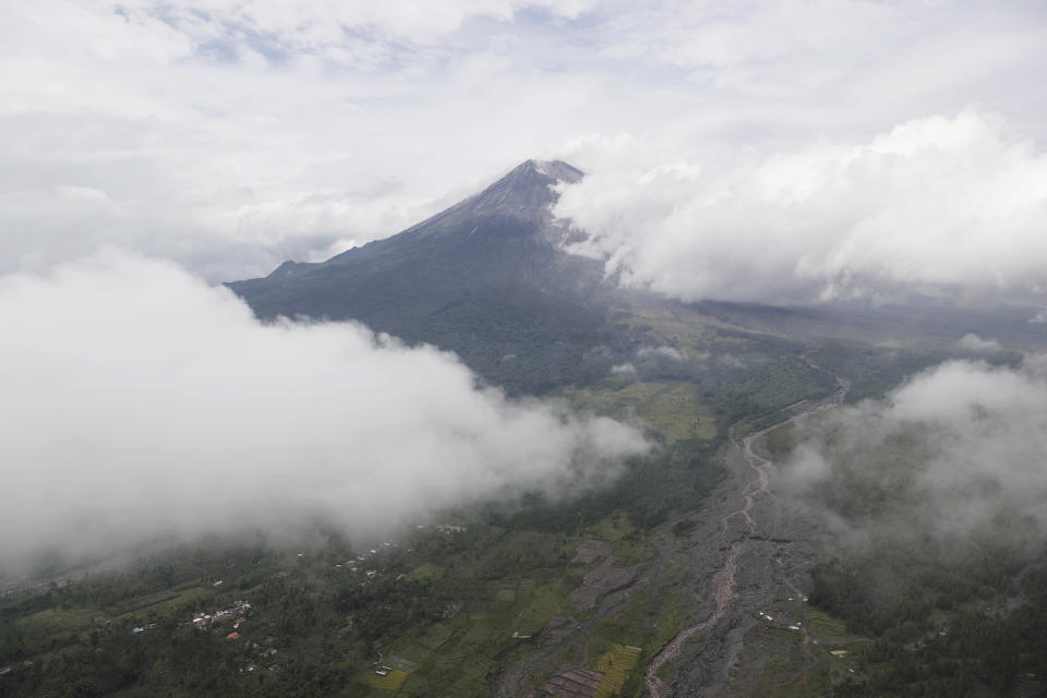 Mount Semeru releases volcanic materials during an eruption as seen from Lumajang district, East Java province, Indonesia, Monday, Dec. 6, 2021. The death toll from eruption of the highest volcano on Indonesia's most densely populated island of Java has risen with scores still missing, officials said Sunday as rain continued to pound the region and hamper the search. (AP Photo/Trisnadi)