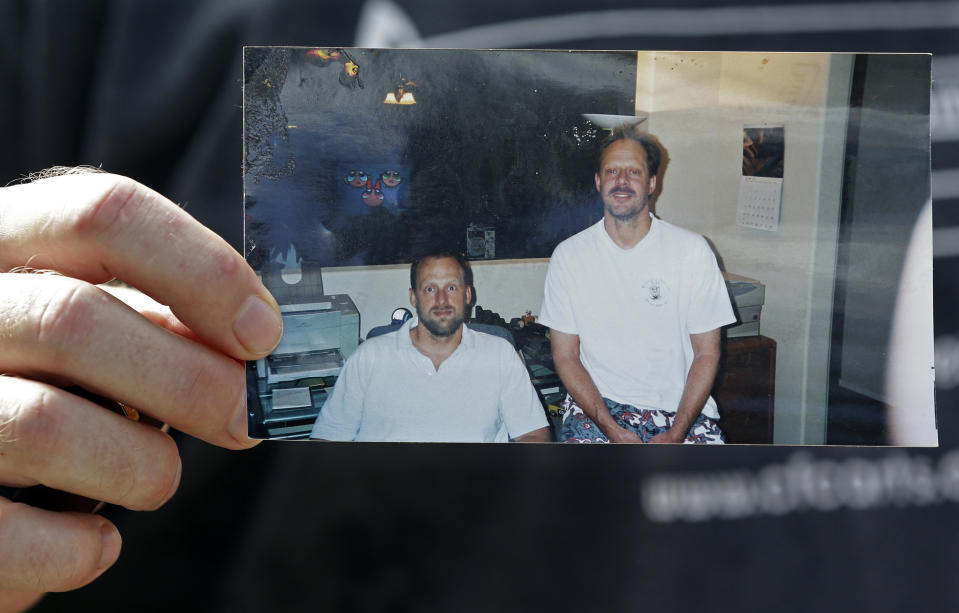 FILE - In this Oct. 2, 2017, file photo, Eric Paddock holds a photo of himself, at left, and his brother, Las Vegas shooter Stephen Paddock, at right, outside his home in Orlando, Fla. Stephen Paddock a high-roller gambler who opened fire in 2017 on concertgoers in Las Vegas had lost tens of thousands of dollars while gambling weeks before the mass shooting and was upset with the way the casinos had been treating him, according to FBI documents made public this week.(AP Photo/John Raoux, File)