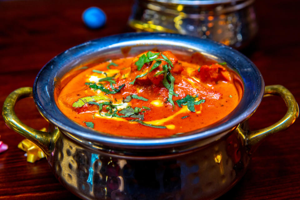 A bowl of creamy butter chicken garnished with cream, butter, and coriander