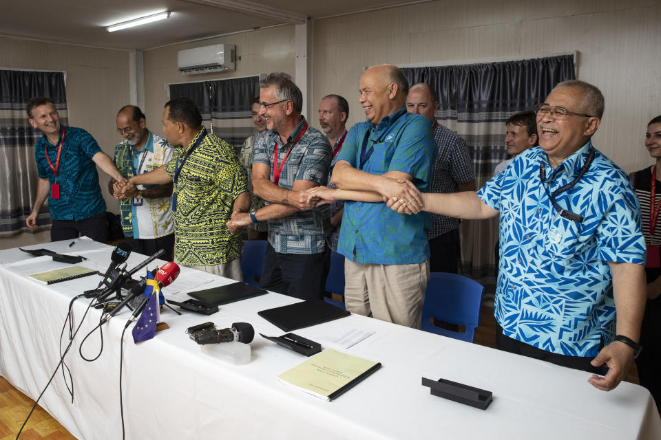 Members of Pacific fishing and community groups join hands after signing an agreement during the Pacific Islands Forum in Nauru, Wednesday, Sept. 5, 2018. The groups signed an agreement with the European Union to improve sustainable fishing and ocean governance in the region. (Jason Oxenham/Pool Photo via AP)