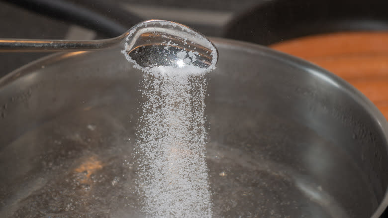 person pouring salt into water