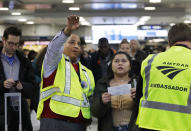 Anthony Navarro, left, an Amtrak Ambassador assisting travelers, helps a woman find the platform for her train, Wednesday, Nov. 21, 2018, in New York's Penn Station. (AP Photo/Mark Lennihan)