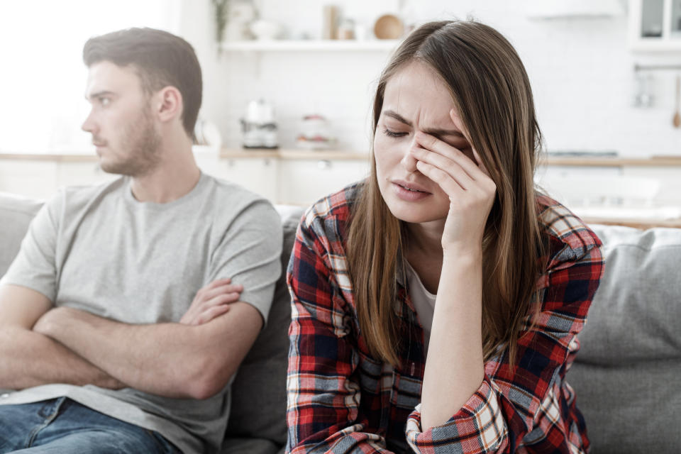 Couple conflict. Stressed crying female sitting on couch with abusive husband after quarrel, ready to divorce