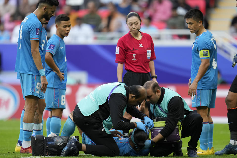 India's Sandesh Jhingan, bottom, receives the first aid after an injuring as the referee Yamashita Yoshimi of Japan and teammates look on during the Asian Cup Group B soccer match between Australia and India at Ahmad Bin Ali Stadium in Doha, Qatar, Saturday, Jan. 13, 2024. (AP Photo/Aijaz Rahi)