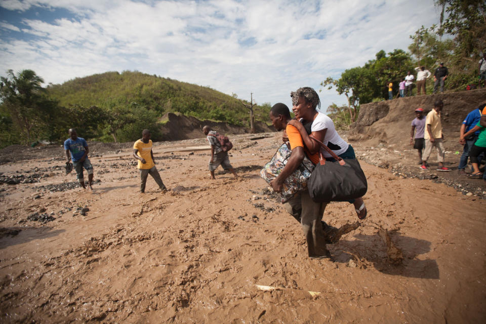 People cross a river after Hurricane Matthew in Ti Goave, Haiti