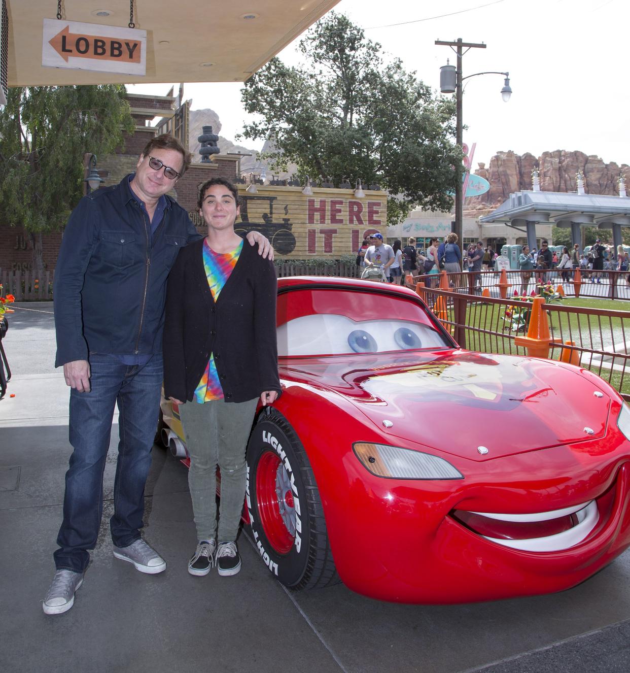 In this photo provided by Disney Parks, actor and television personality Bob Saget and daughter Jennifer Belle Saget meet Lightning McQueen in Cars Land at Disney California Adventure Park in Anaheim, Calif. on March 19, 2016.