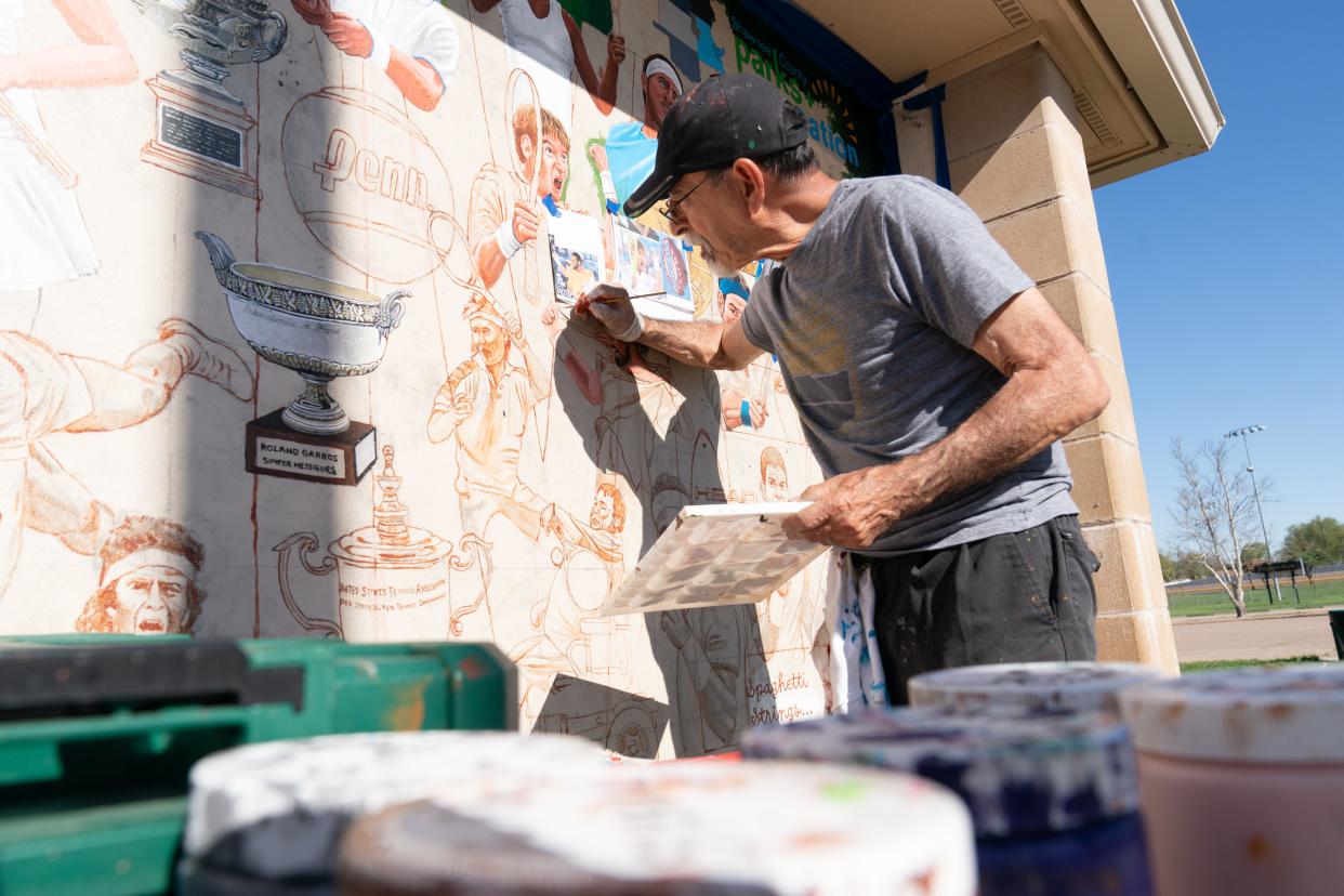 Topeka artist Andy Valdivia on Wednesday works details of former tennis star Patrick Rafter into a mural at Kossover Tennis Center. Valdivia, a tennis player himself, was commissioned by the center to showcase the sport and Topeka's involvement.