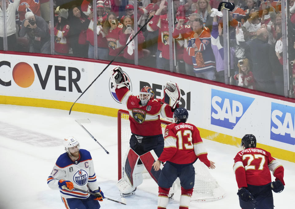 Florida Panthers goaltender Sergei Bobrovsky (72) and forward Sam Reinhart (13) celebrate after winning the NHL hockey Stanley Cup as Edmonton Oilers forward Connor McDavid (97) looks on after Game 7 of the Final in Sunrise, Fla., Monday, June 24, 2024. (Nathan Denette/The Canadian Press via AP)