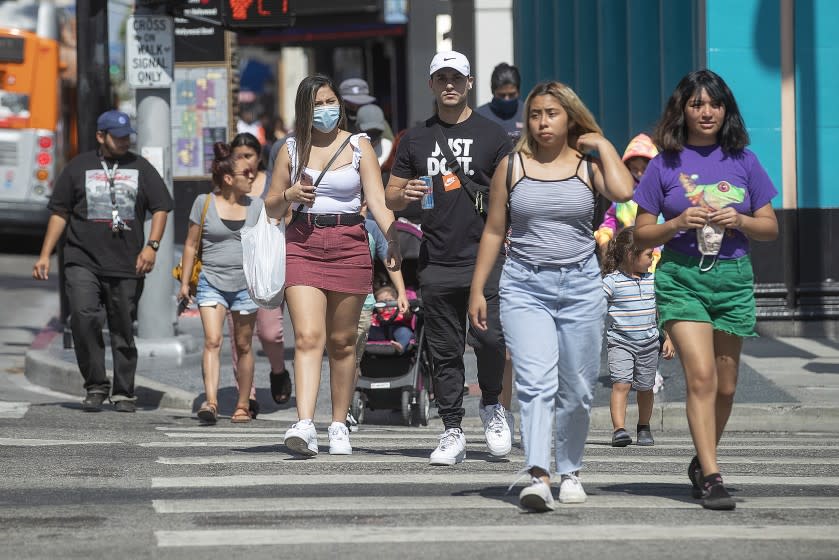 HOLLYWOOD, CA-JUNE 18, 2020-Pedestrians, cross the intersection of Hollywood Blvd. and Highland Ave. in Hollywood. Gov. Gavin Newsom on Thursday ordered all Californians to wear face coverings while in public, following growing concerns that an increase in coronavirus cases has been caused by residents failing to voluntarily take that precaution. (Mel Melcon/Los Angeles Times)