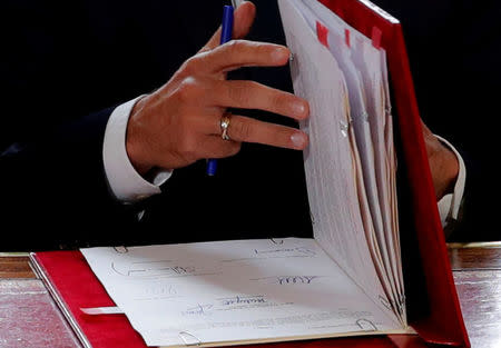 FILE PHOTO: French President Emmanuel Macron signs documents in front of the media to promulgate a new labour bill in his office at the Elysee Palace in Paris, France, September 22, 2017. REUTERS/Philippe Wojazer/File Photo