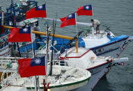 A fisherman raises a Taiwanese national flag as several dozen fishing boats set out from the Suao harbor, northeastern Taiwan, to the disputed islands in the East China Sea, Monday, Sept. 24, 2012. The islands, called Senkaku in Japan and Diaoyu in China, are controlled by Japan but also claimed by China and Taiwan, and have been a key part of simmering regional tensions over rival territorial claims. (AP Photo/Wally Santana)