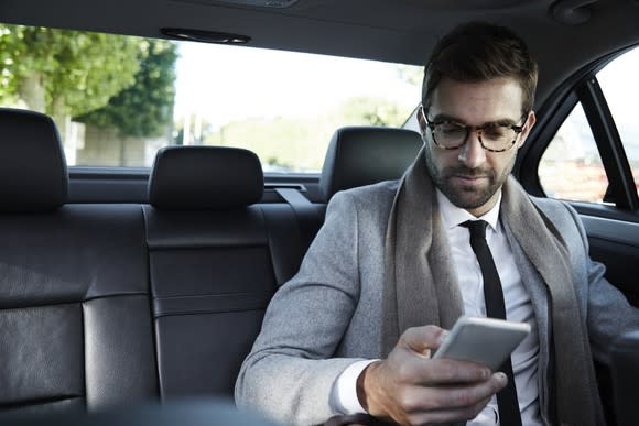 A man using a smartphone in the back of a cab.