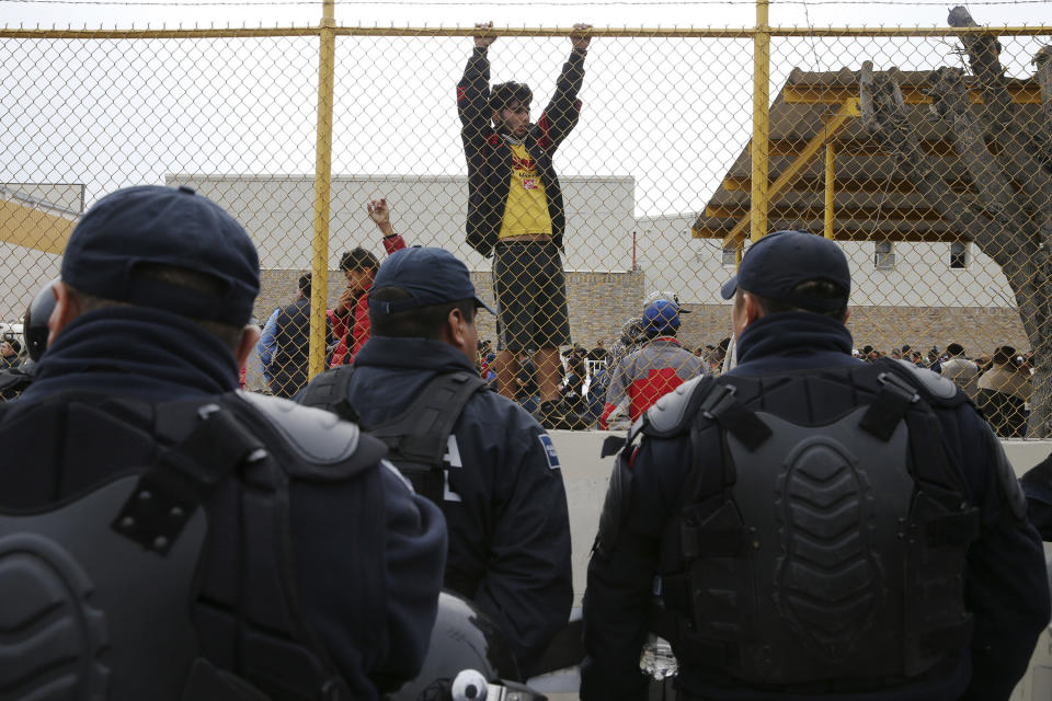 Central American immigrants hang around by the fence line of a shelter guarded by Mexican Federal police in riot gear in Piedras Negras, Mexico, Tuesday, Feb. 5, 2019. A caravan of about 1,600 Central American migrants camped Tuesday in the Mexican border city of Piedras Negras, just west of Eagle Pass, Texas. The governor of the northern state of Coahuila described the migrants as "asylum seekers," suggesting all had express intentions of surrendering to U.S. authorities. (Jerry Lara/The San Antonio Express-News via AP)