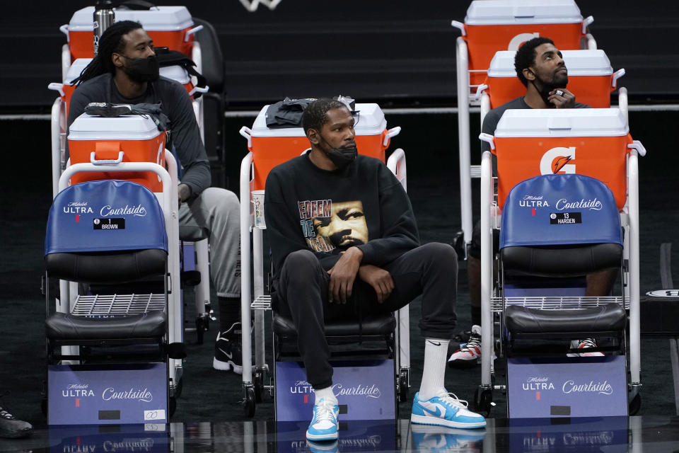 Brooklyn Nets DeAndre Jordan, left, Kevin Durant, center, and Kyrie Irving watch their teammates play the Sacramento King during the second half of an NBA basketball game in Sacramento, Calif., Monday, Feb. 15, 2021. Durant did not play due to an injury. The Nets won 136-125. (AP Photo/Rich Pedroncelli)