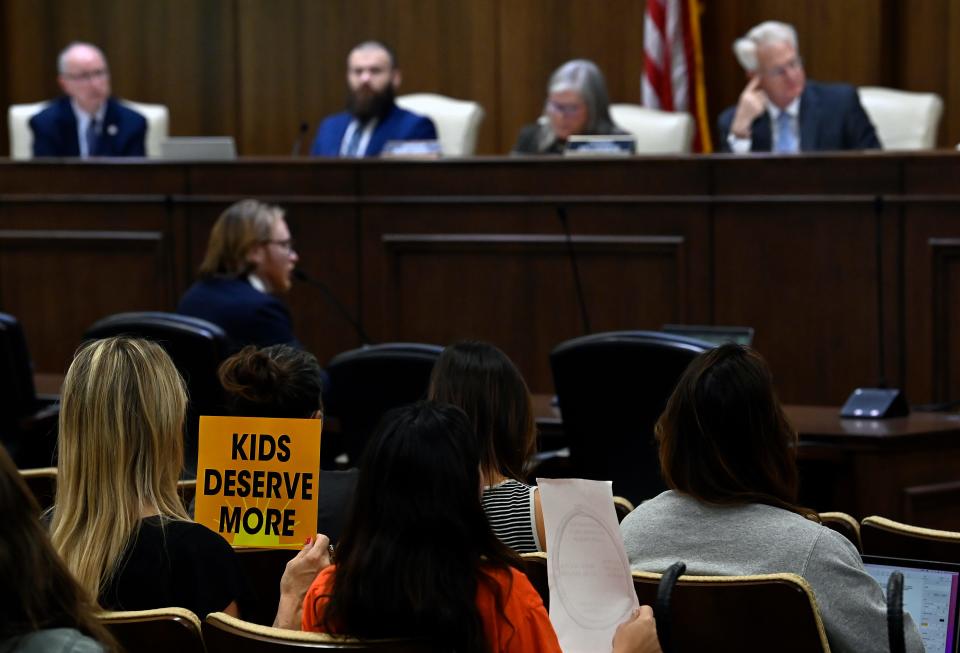 Eleese Meschery, bottom left, holds a sign as she listens to Austin Reid, senior legislative director for the National Conference of State Legislatures, during a joint working group on federal education funding at the Cordell Hull State Office Building on Wednesday, Nov. 8, 2023, in Nashville, Tenn.