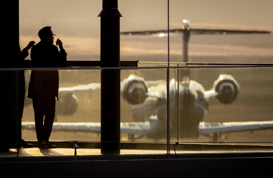 A man watches a plane pass by as he stands on the balcony of a building at the airport in Frankfurt, Germany, Thursday, Feb. 29, 2024. (AP Photo/Michael Probst)