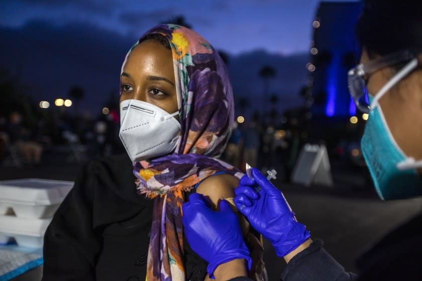 SANTA ANA , CA - MAY 01: Sara Ahmed, 29, of Anaheim, left, is getting vaccinated by EMT Daniella Gochuico, right, during a COVID vaccine/taco truck party at Islamic Center of Santa Ana Saturday night., May 1, 2021 in Santa Ana, CA. (Francine Orr / Los Angeles)