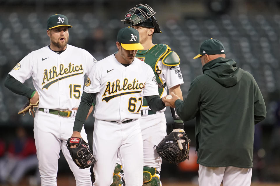 Oakland Athletics manager Mark Kotsay, right, takes the ball from pitcher Zach Logue (67) during a pitching change during the fifth inning of a baseball game against the Minnesota Twins in Oakland, Calif., Monday, May 16, 2022. (AP Photo/Jeff Chiu)