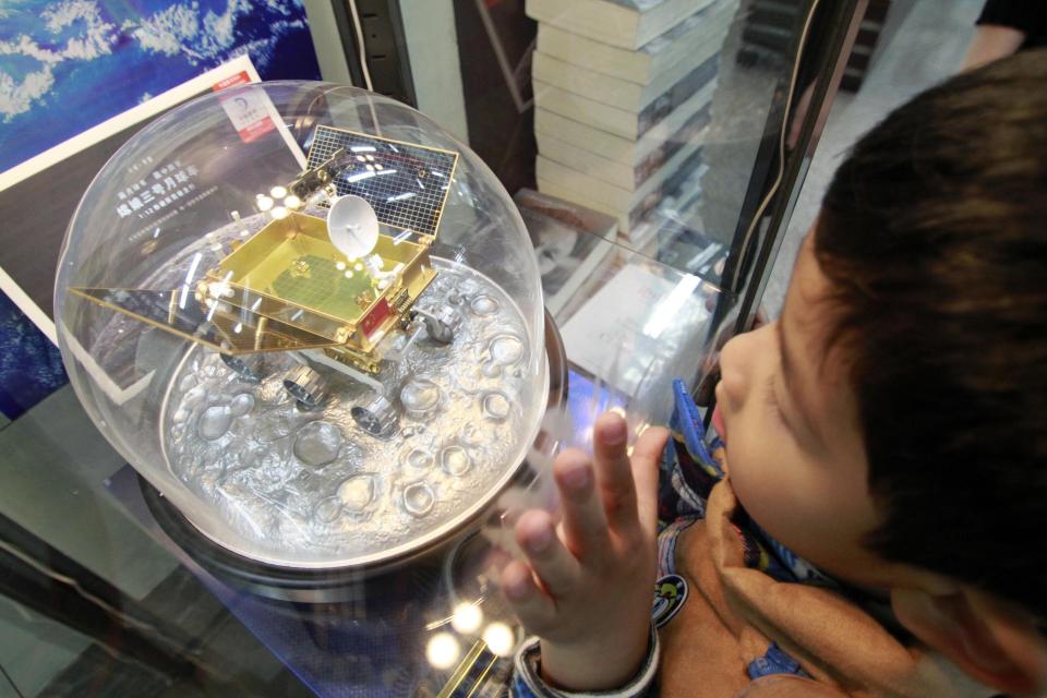 A boy looks at a golden scale model of China's lunar rover "Yutu", or Jade Rabbit, on display in a glass case in Nanjing, Jiangsu province December 14, 2013. China launched its first ever extraterrestrial landing craft into orbit en route for the moon in the small hours of December 2, in a major milestone for its space programme. The rover, carried by the Chang'e-3 lunar probe, is expected to land on the moon on Saturday evening, 12 days after it blasted off from the earth, Xinhua News Agency reported. (REUTERS/Stringer)