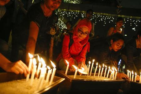 People place their candles after a candlelight vigil for the passengers of the missing Malaysia Airlines MH370 in central Kuala Lumpur March 27, 2014. REUTERS/Athit Perawongmetha