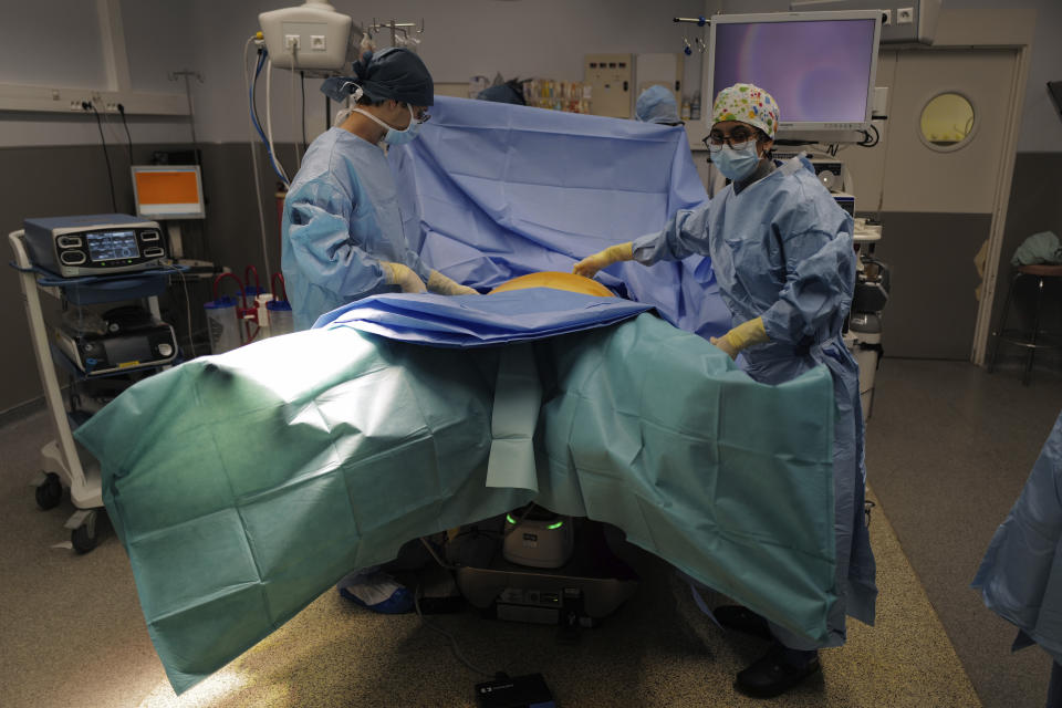 Surgeon Lara Ribeiro Parenti, right, prepares for the surgery of Caroline Erganian at Bichat Hospital, AP-HP, in Paris, Wednesday, Dec. 2, 2020. (AP Photo/Francois Mori)