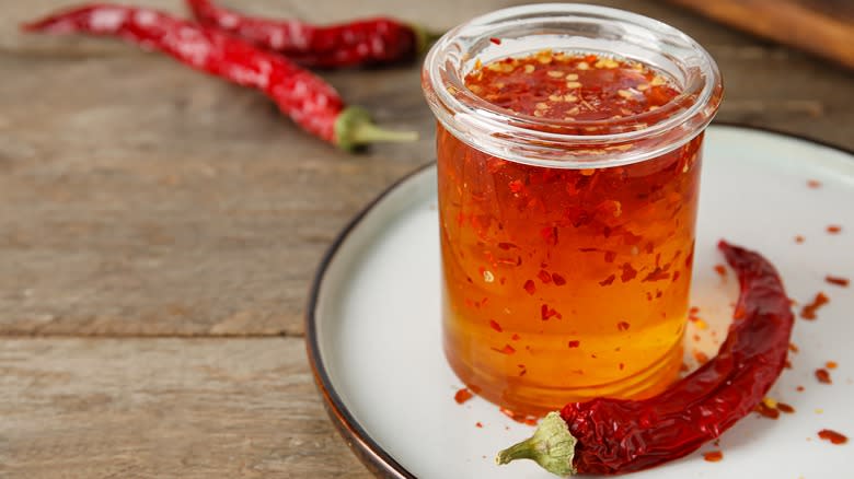 A jar of hot honey on plate with pepper