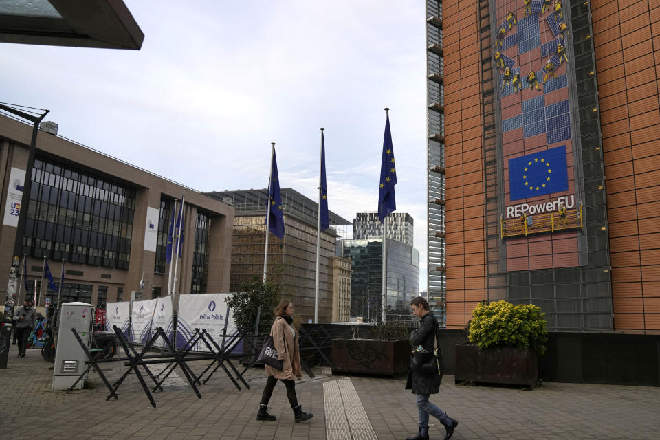 Two people walk past EU headquarters prior to an EU summit in Brussels, Thursday, Oct. 26, 2023. European Union leaders gather Thursday for a two day meeting to discuss, among other issues, Ukraine and the impact of the war between Israel and Hamas. (AP Photo/Virginia Mayo)