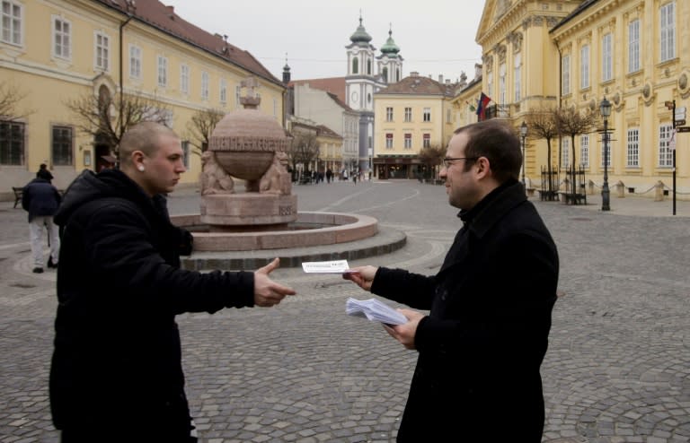 An activist of "Print It Yourself!" hands out home-printed news pamphlets in Szekesfehervar's main square