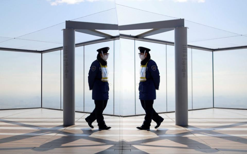 A security guard wearing a protective face mask is reflected on the surface of an object, amid the coronavirus outbreak, at an observation deck - REUTERS/Issei Kato