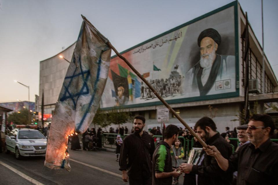 Iranian demonstrators burn an Israeli flag in Tehran on Oct. 17, 2023. <a href="https://www.gettyimages.com/detail/news-photo/tehran-iran-in-the-aftermath-of-the-bombing-of-gazas-al-news-photo/1734088645?adppopup=true" rel="nofollow noopener" target="_blank" data-ylk="slk:Hossein Beris/Middle East Images/AFP via Getty Images;elm:context_link;itc:0" class="link ">Hossein Beris/Middle East Images/AFP via Getty Images</a>