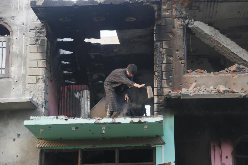 A Kashmiri Muslim villager cleans the debris of a house which was damaged in a gunbattle at Shopian, south of Srinagar, Indian controlled Kashmir, Tuesday, Nov. 20, 2018. Four rebels and an Indian army commando were killed in fighting in disputed Kashmir on Tuesday, triggering anti-India protests and clashes in the restive region. (AP Photo/Mukhtar Khan)